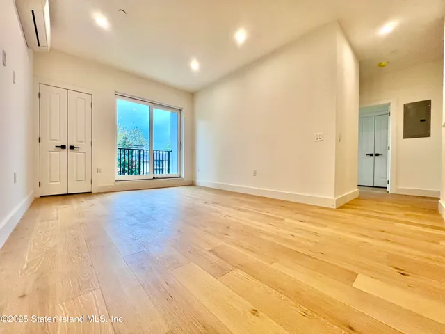 a view of an empty room with wooden floor and windows