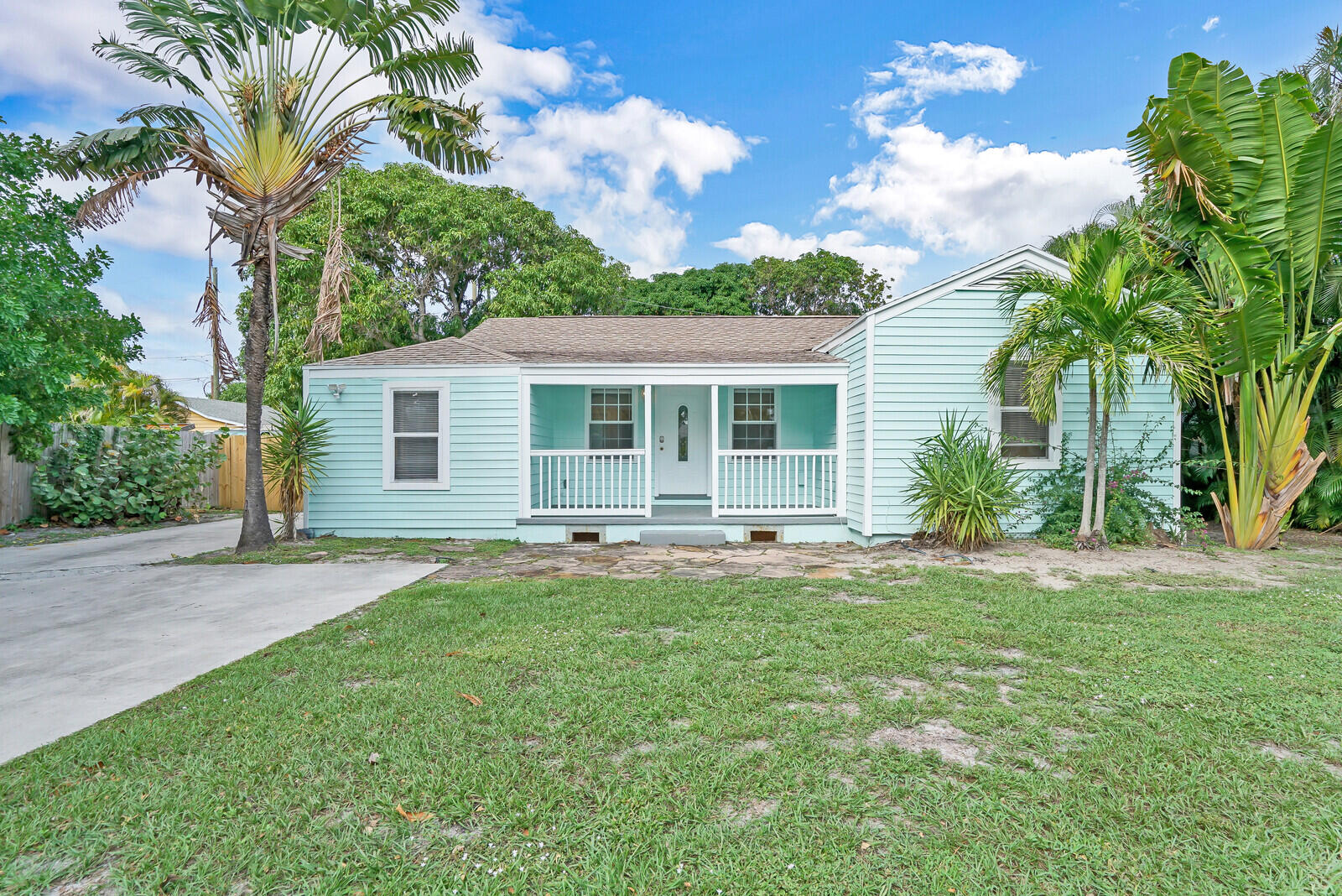 front view of a house with a yard and palm trees