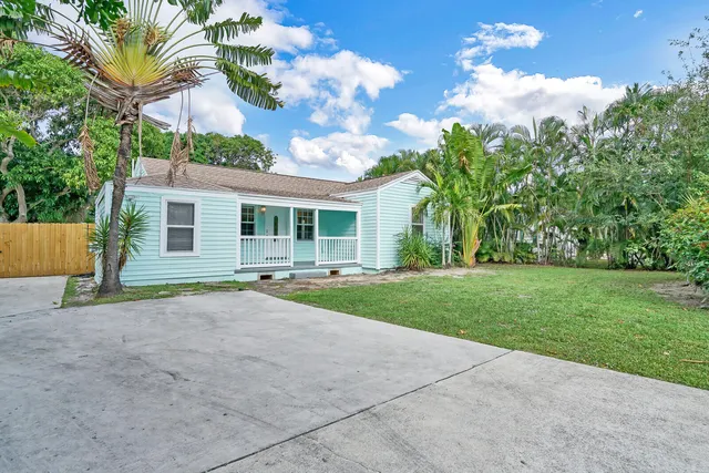 a view of a house with a backyard and a tree