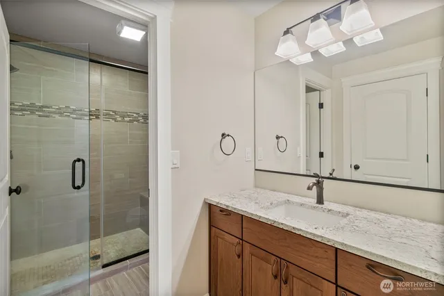 a bathroom with a granite countertop sink a mirror and shower