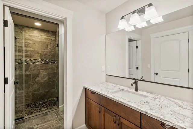 a bathroom with a granite countertop sink a mirror and shower