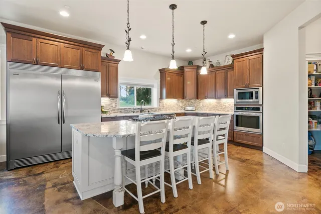 a kitchen with kitchen island granite countertop a refrigerator and wooden floor