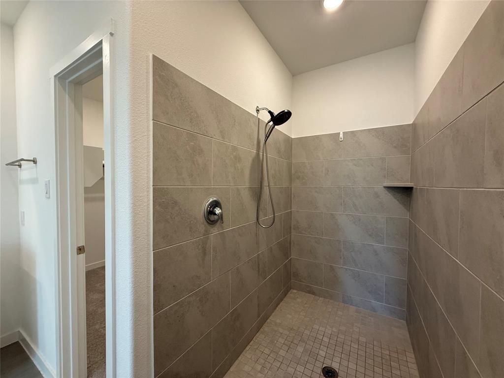 3025 Timber Rdg Drive Anna, TX 75409 - Photo 19 of 23 Tiled shower with a rainfall showerhead, handheld shower fixture, and a built-in shelf