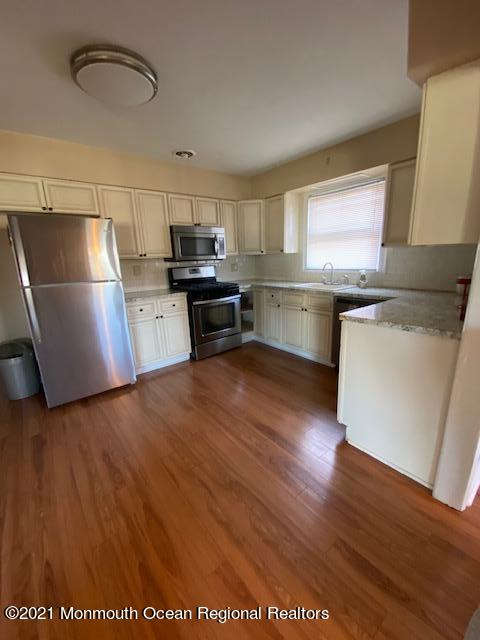 9 Howland Avenue Long Branch, NJ 07740 - Photo 7 of 18 a kitchen with stainless steel appliances a refrigerator a stove a sink cabinets and wooden floor