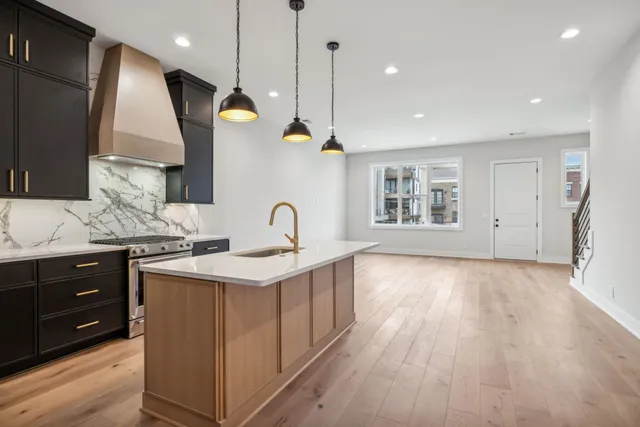a kitchen with stainless steel appliances granite countertop a sink a stove and a wooden floors