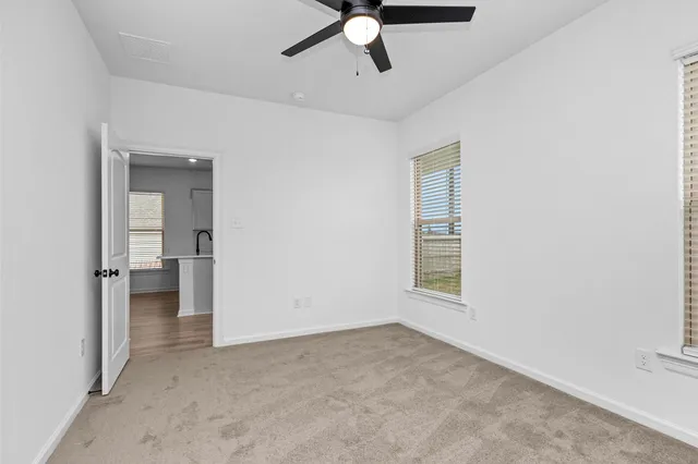 an empty room that has a window and a ceiling fan