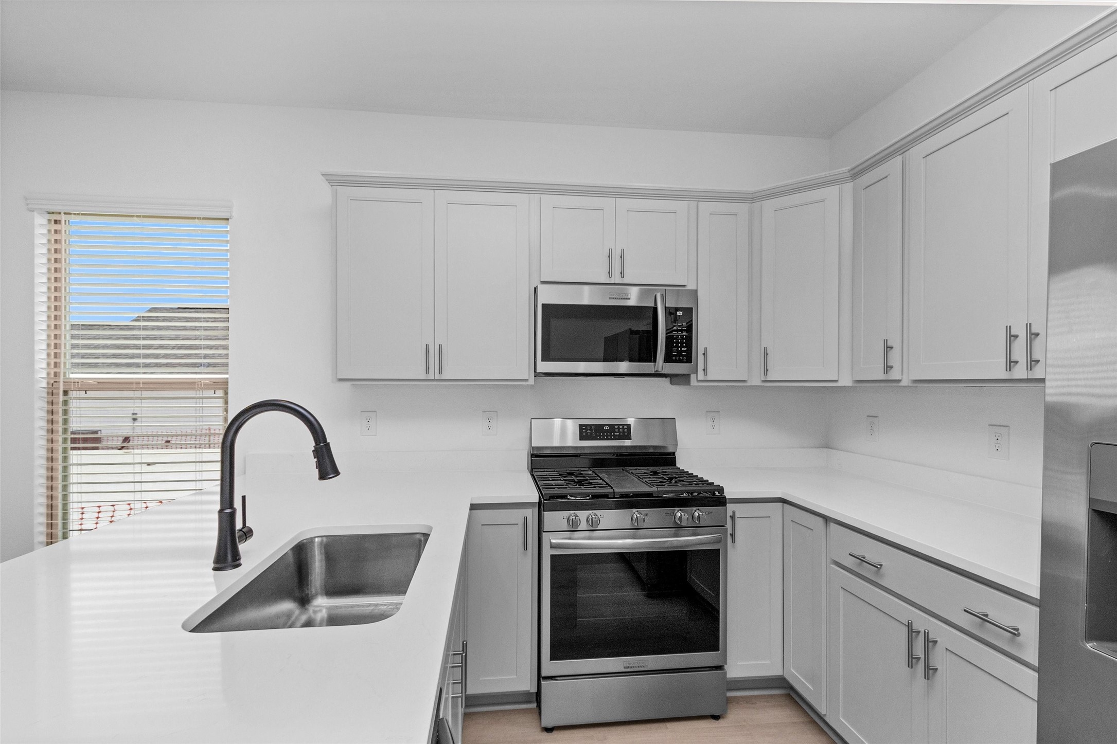 40700 Pessi Road Magnolia, TX 77354 - Photo 10 of 29 a kitchen with white cabinets a sink and a stove with wooden floor
