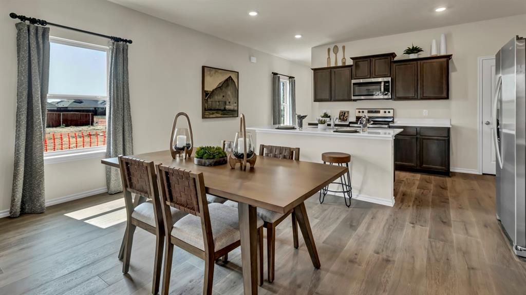 124 Pheasant Run Road Terrell, TX 75160 - Photo 17 of 35 Open-concept dining area featuring wood-finish flooring, a contemporary window with drapes, a kitchen with dark cabinetry, stainless steel appliances, and a breakfast bar with a white countertop