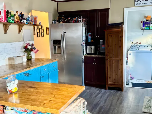 a kitchen with stainless steel appliances granite countertop a refrigerator and a wooden floor