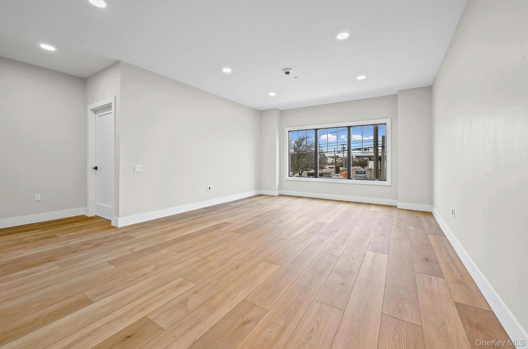 80 Division Street, Unit 103 Patchogue, NY 11772 - Photo 5 of 9 a view of an empty room with a window and wooden floor