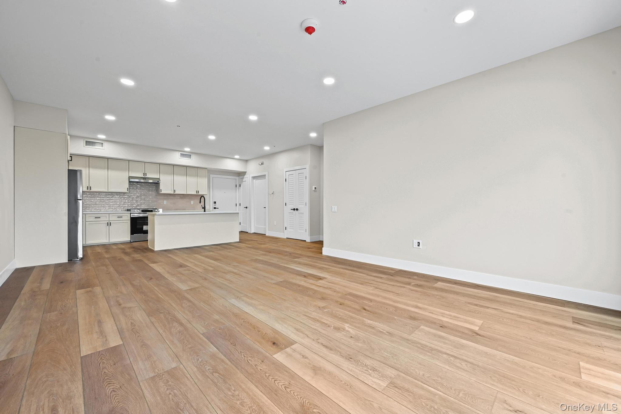 80 Division Street, Unit 103 Patchogue, NY 11772 - Photo 6 of 9 a view of kitchen with kitchen island a sink wooden floor and view living room
