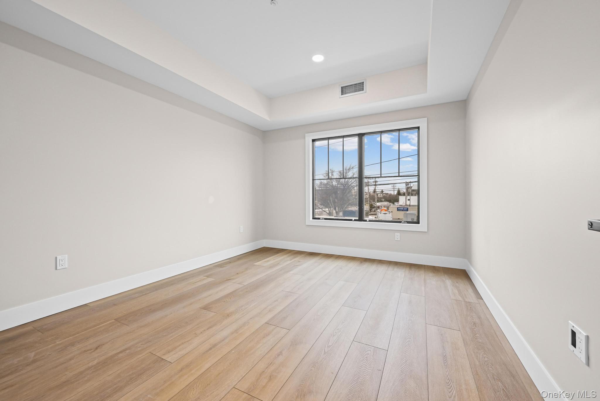 80 Division Street, Unit 103 Patchogue, NY 11772 - Photo 7 of 9 an empty room with wooden floor and windows
