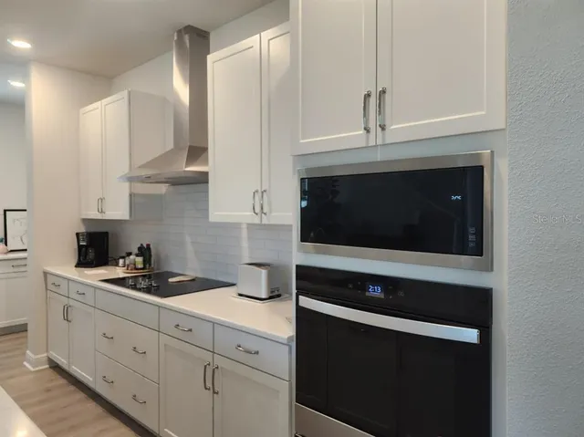 a kitchen with granite countertop white cabinets and stainless steel appliances