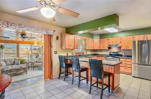 a kitchen with stainless steel appliances kitchen island granite countertop a table chairs sink and cabinets