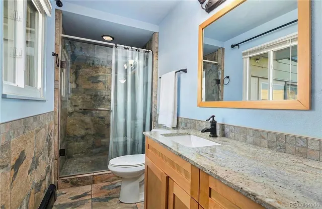 a bathroom with a granite countertop sink toilet and shower