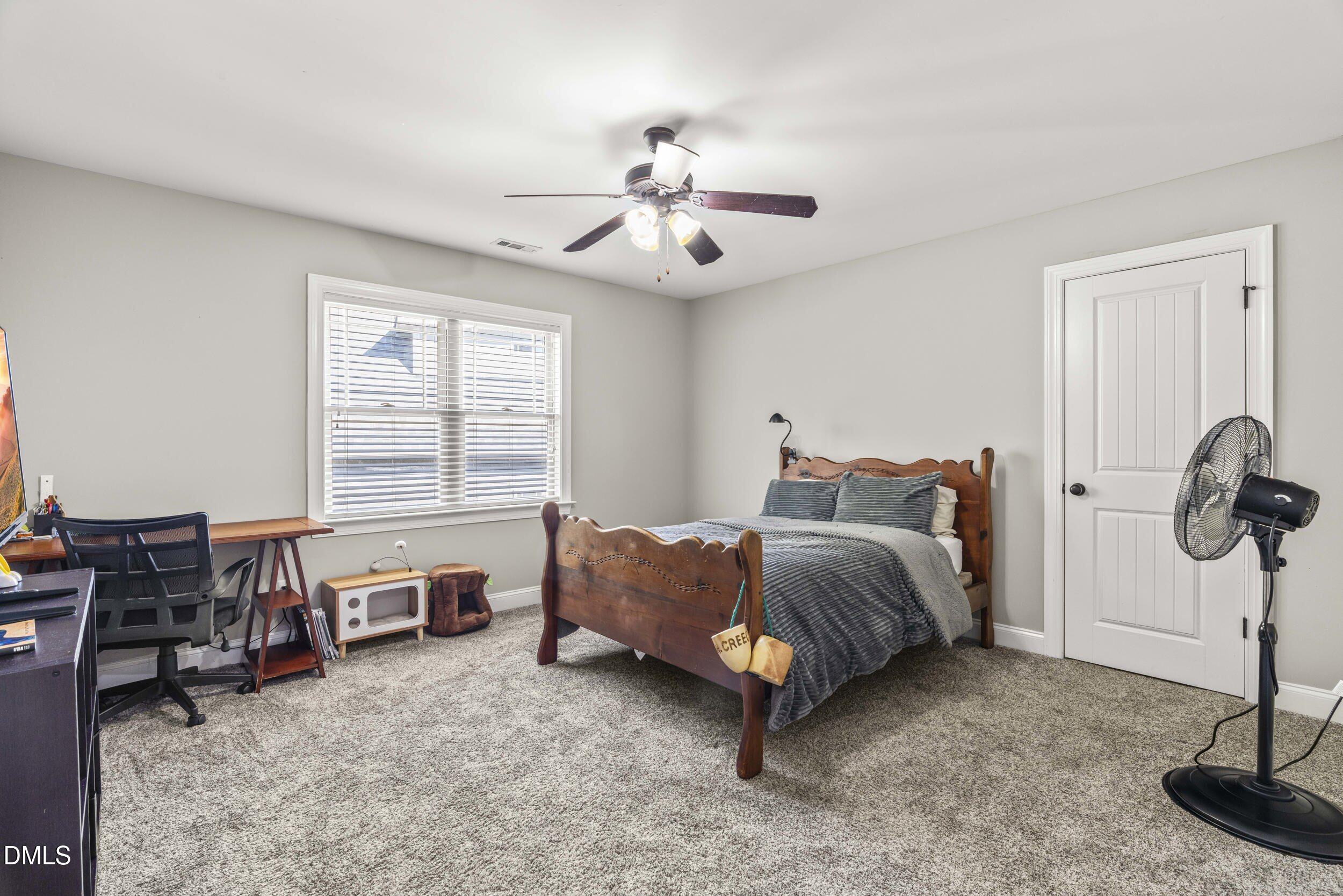 648 Fieldtrial Circle Garner, NC 27529 - Photo 38 of 56 a spacious bedroom with a bed and a chandelier