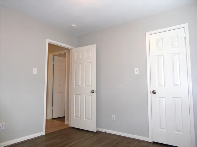 an empty room with wooden floor & closet area