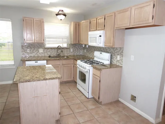 a kitchen with granite countertop white cabinets and white appliances