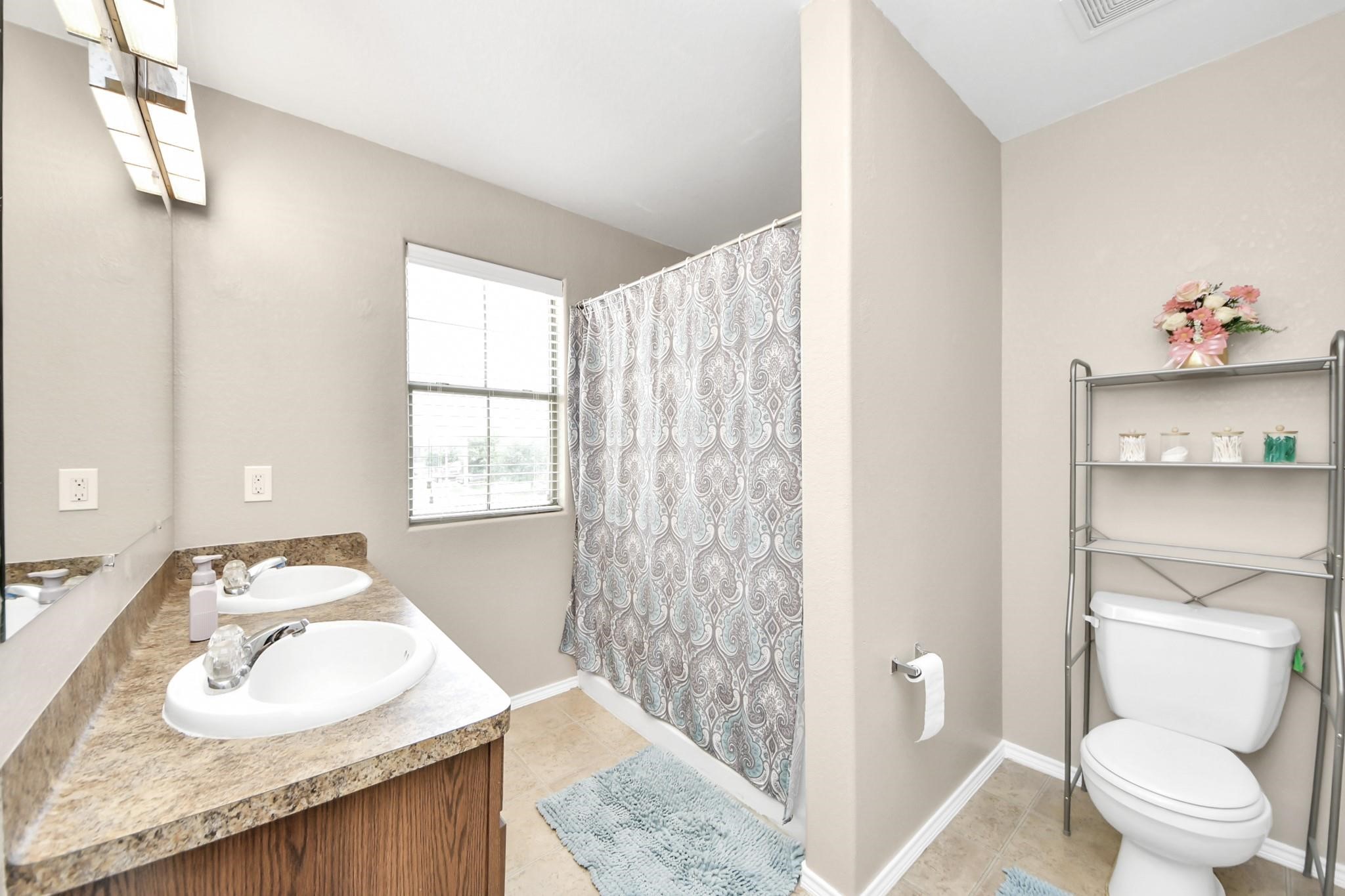 16542 Peyton Ridge Circle Houston, TX 77049 - Photo 11 of 16 a bathroom with a granite countertop sink a toilet and a mirror