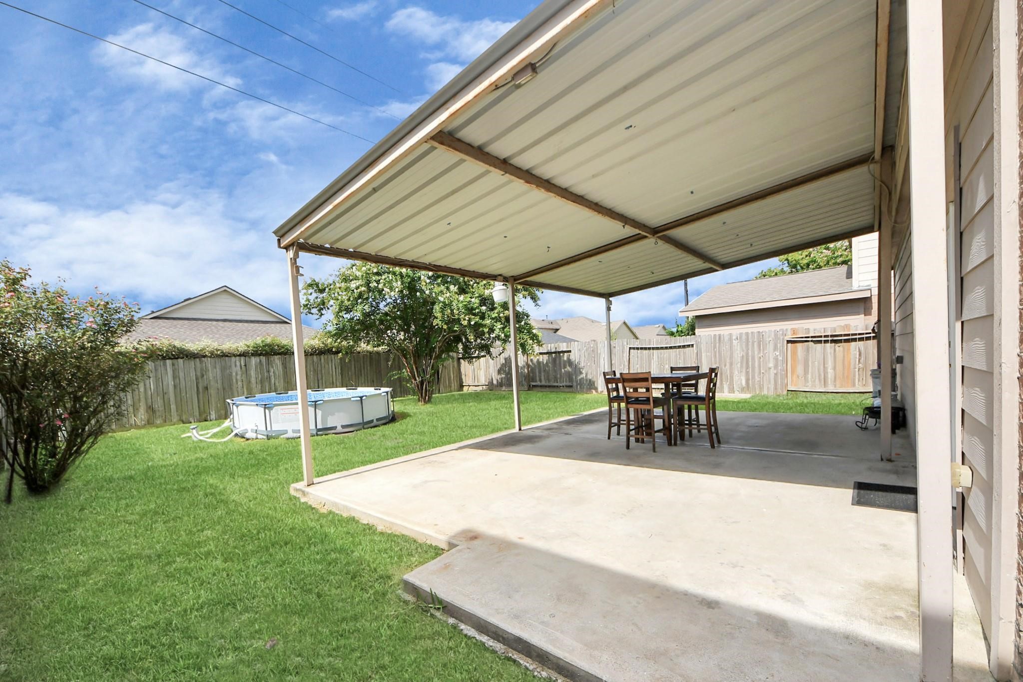 16542 Peyton Ridge Circle Houston, TX 77049 - Photo 15 of 16 a view of a backyard with table and chairs under an umbrella with a small yard