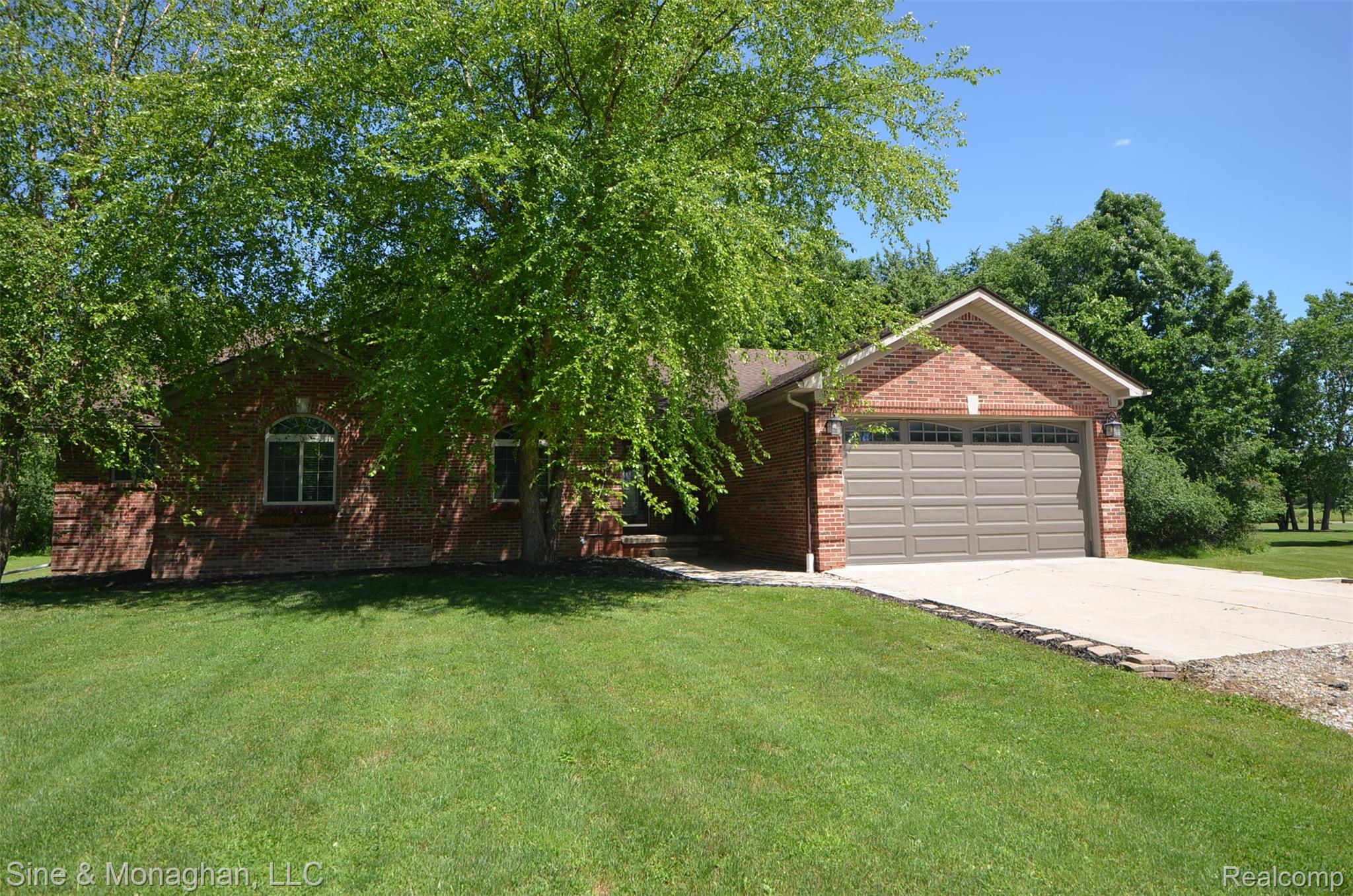 76152 Burman Road Richmond, MI 48062 - Photo 3 of 75 Brick exterior featuring a two-car garage with a brown door, concrete driveway, and arched window