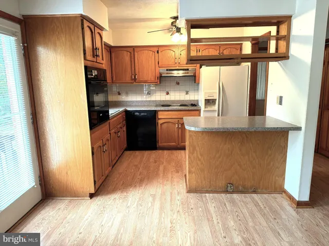 a kitchen with stainless steel appliances granite countertop a refrigerator a sink and wooden cabinets