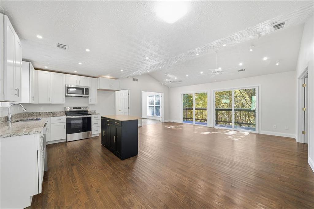 1512 Upper Sassafras Road Jasper, GA 30143 - Photo 11 of 35 a large kitchen with stainless steel appliances granite countertop a stove a sink a refrigerator and white cabinets with wooden floor