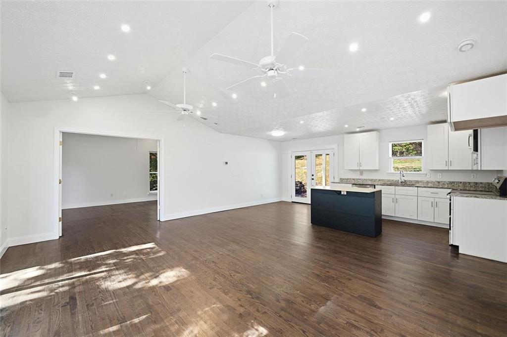 1512 Upper Sassafras Road Jasper, GA 30143 - Photo 16 of 35 a large white kitchen with kitchen island a sink dishwasher and a stove with wooden floor