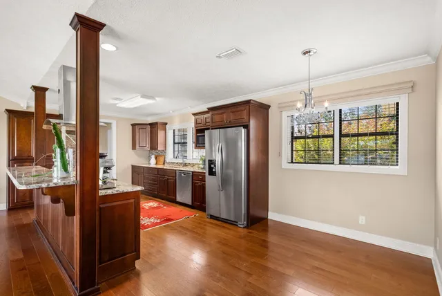 a kitchen with stainless steel appliances granite countertop a refrigerator a sink dishwasher and a oven with wooden floor