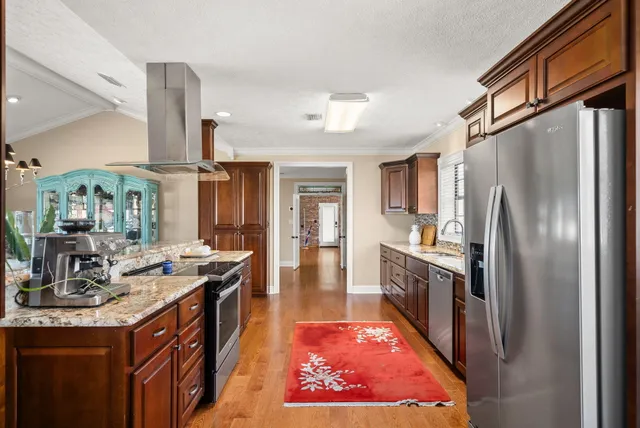 a kitchen with stainless steel appliances granite countertop a refrigerator a stove and a sink