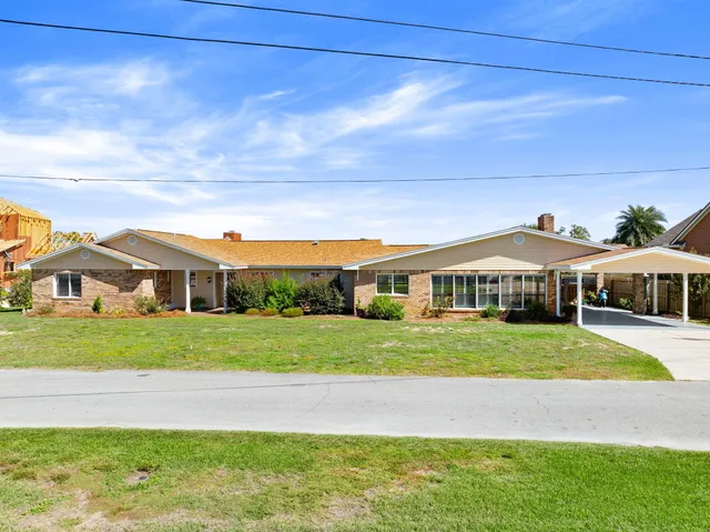 a view of a big house with a big yard and large trees