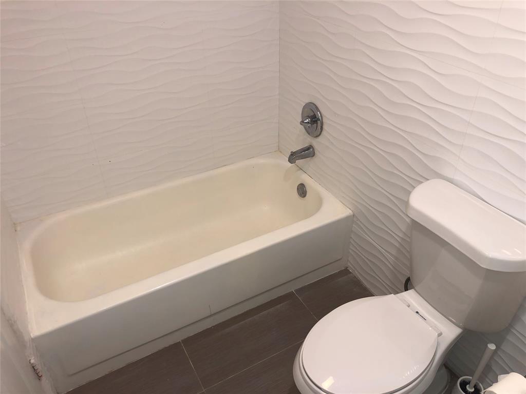 651 Lyons Road, Unit 10104 Coconut Creek, FL 33063 - Photo 5 of 9 a white toilet sitting next to a bath tub