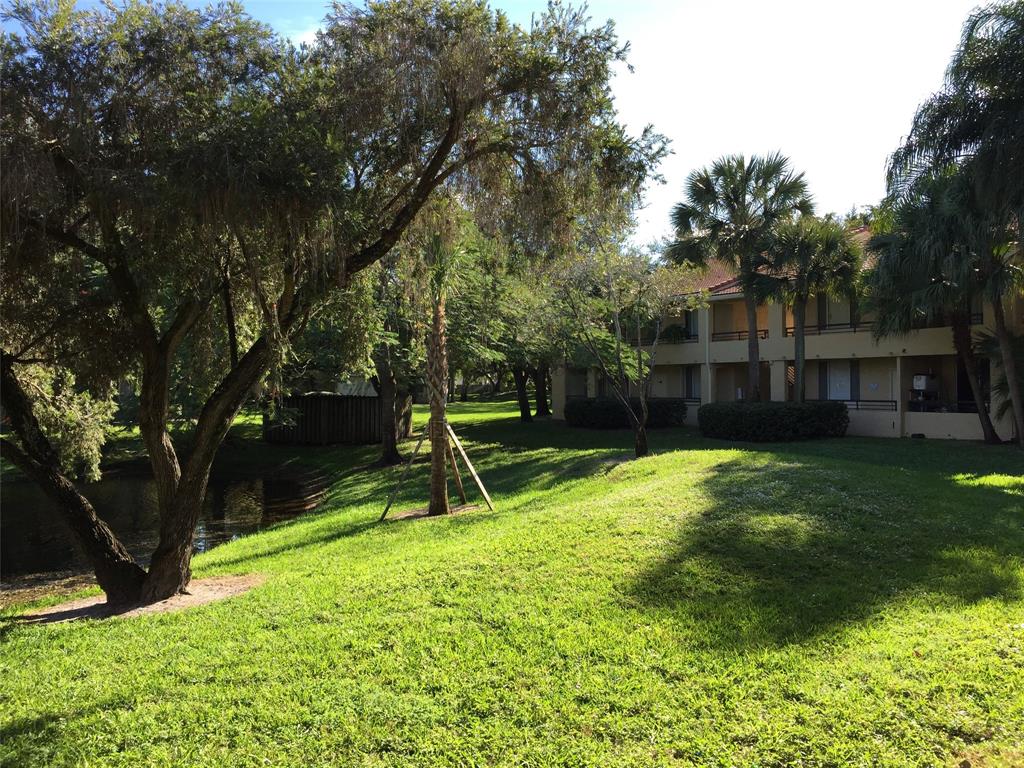 651 Lyons Road, Unit 10104 Coconut Creek, FL 33063 - Photo 7 of 9 a view of a backyard with a slide and a large tree