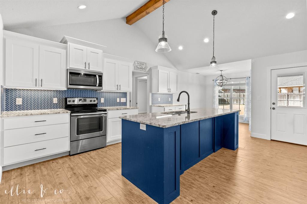 Kitchen with stainless steel appliances, beam ceiling, white cabinets, light wood-style flooring, and decorative backsplash