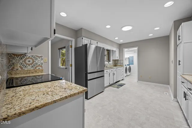 a kitchen with stainless steel appliances kitchen island granite countertop a refrigerator and a sink