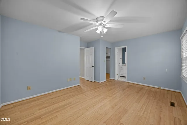 a view of an empty room with chandelier fan and wooden floor