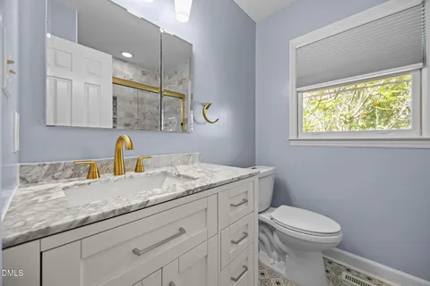 a bathroom with a granite countertop toilet sink and mirror