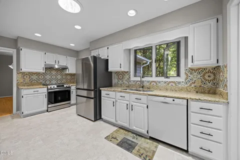 a kitchen with granite countertop a refrigerator oven a sink and dishwasher with wooden floor