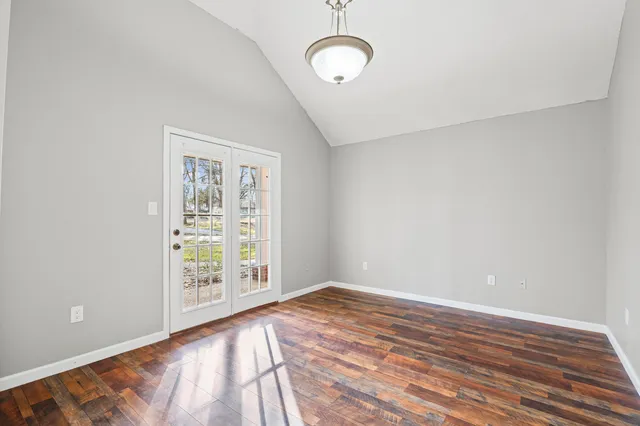 a view of an empty room with wooden floor and windows