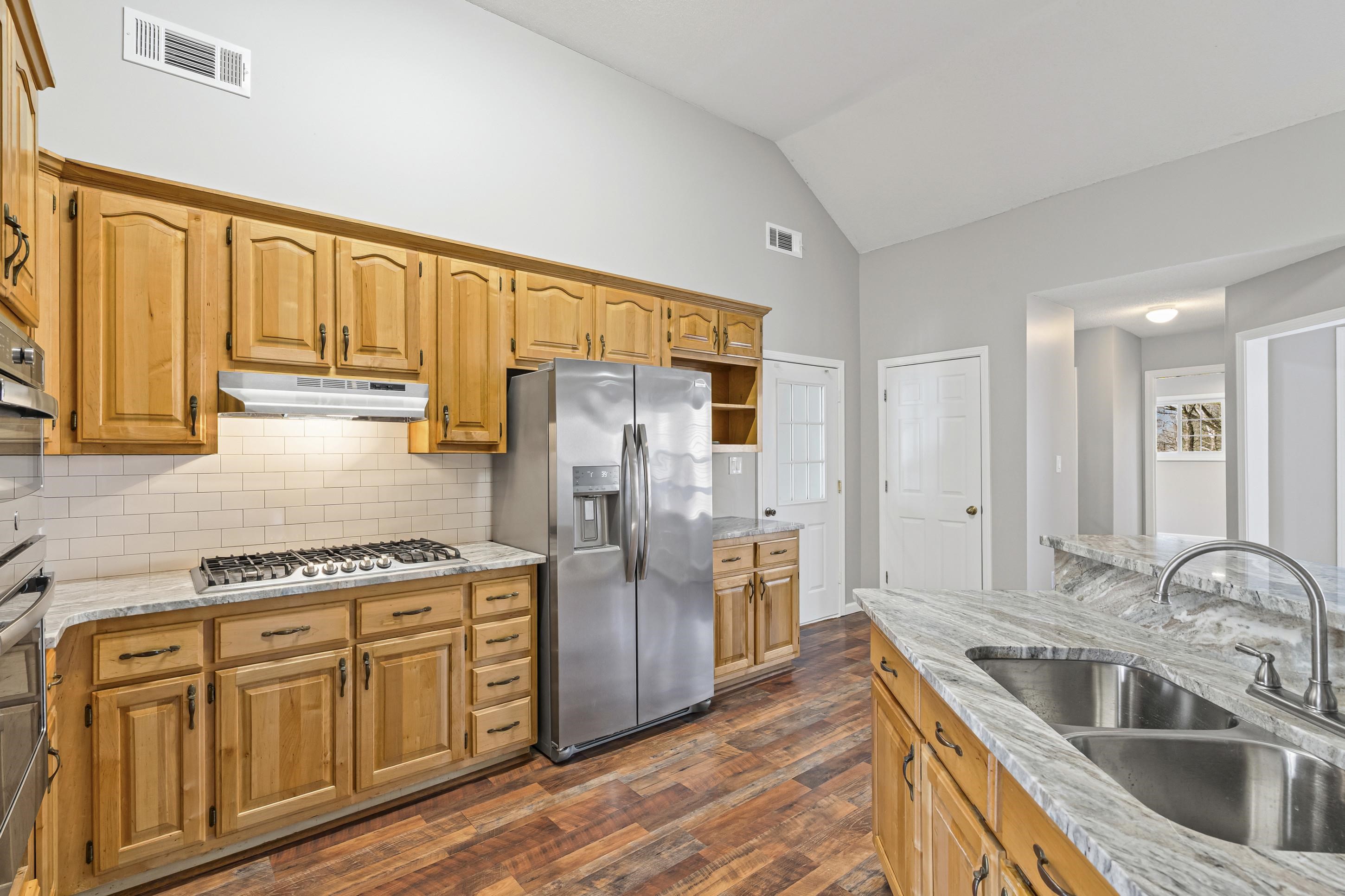 225 Poplar Grove Church Road Drummonds, TN 38023 - Photo 7 of 30 a kitchen with stainless steel appliances granite countertop a refrigerator a sink dishwasher and wooden cabinets with wooden floor