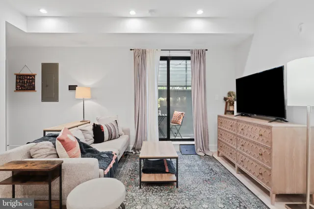 a living room with furniture a flat screen tv and kitchen view