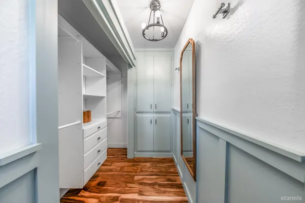 a view of hallway with mirror and wooden floor