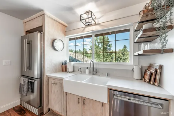 a kitchen with stainless steel appliances a sink a refrigerator a window and cabinets