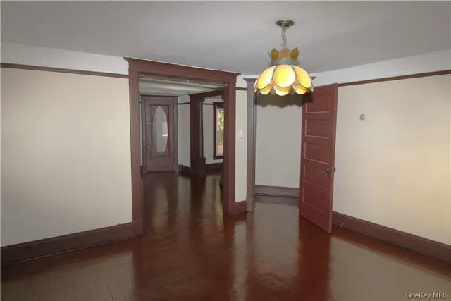 a view of a hallway with wooden floor and chandelier