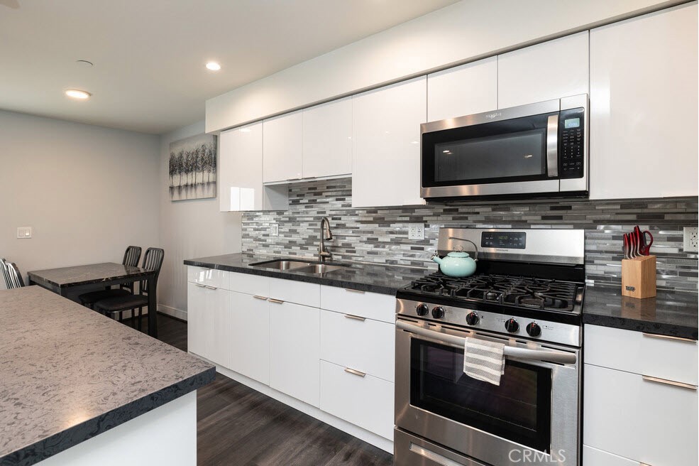 2651 South Hobart Boulevard, Unit 6 Los Angeles, CA 90018 - Photo 2 of 8 a kitchen with stainless steel appliances kitchen island granite countertop a stove and a microwave