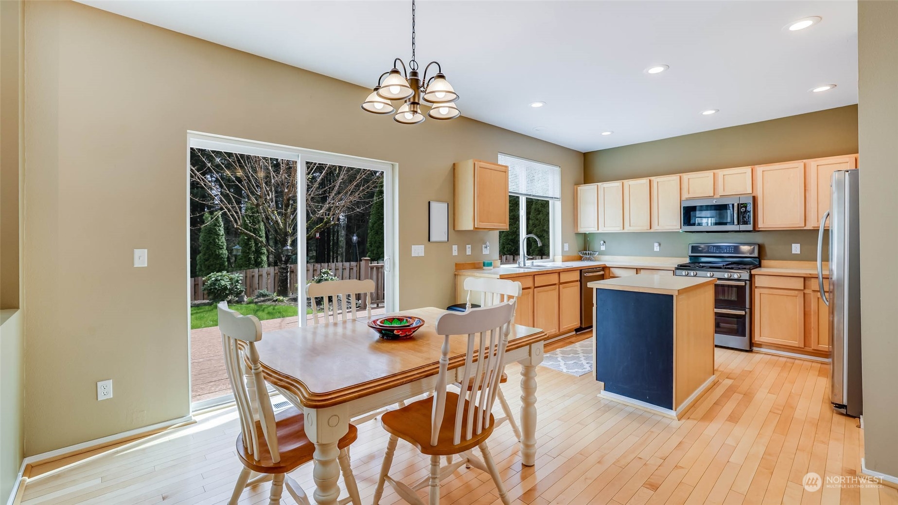 28120 Maple Ridge Way Southeast Maple Valley, WA 98038 - Photo 8 of 36 a kitchen with stainless steel appliances granite countertop a stove a refrigerator a sink dishwasher a dining table and chairs with wooden floor