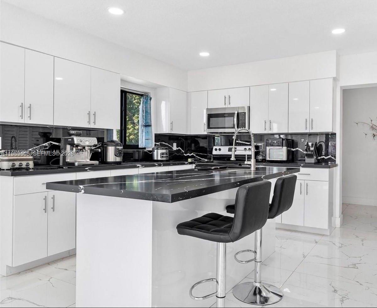 19530 Southwest 210th Street Miami, FL 33187 - Photo 7 of 20 a kitchen with stainless steel appliances granite countertop a stove a sink a microwave a refrigerator and white cabinets