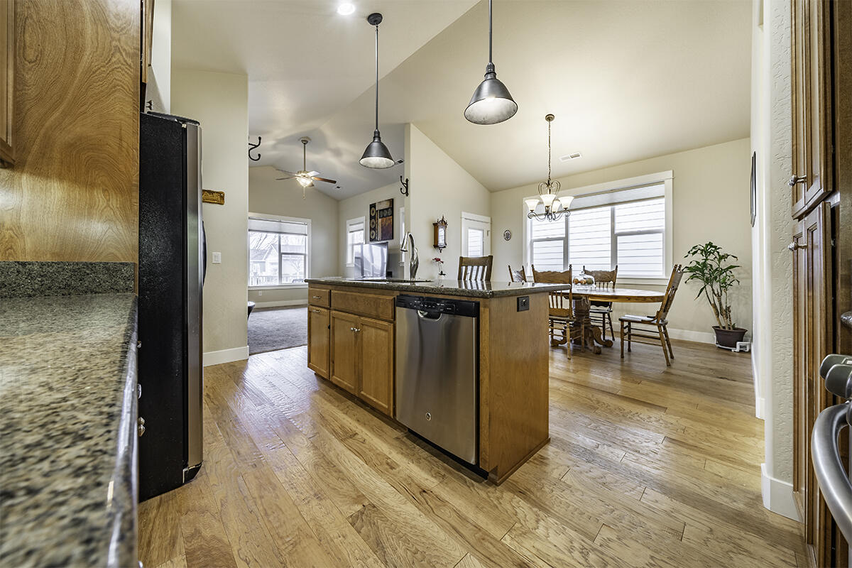 1078 North Haskell Street Central Point, OR 97502 - Photo 10 of 25 a kitchen with stainless steel appliances granite countertop a refrigerator a sink dishwasher a stove and a dining table with wooden floor