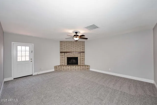 a view of an empty room with a fireplace and a window