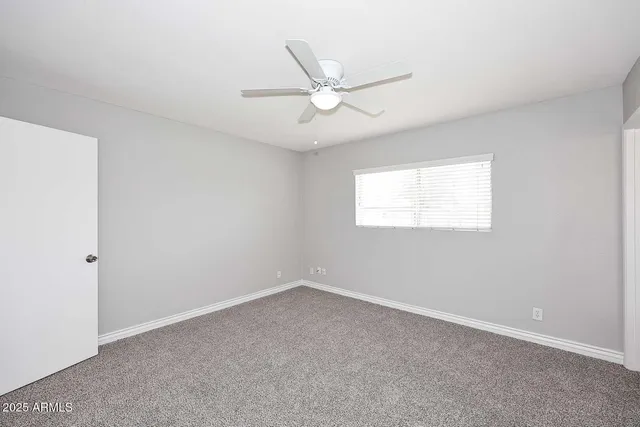 an empty room with a window and a fan